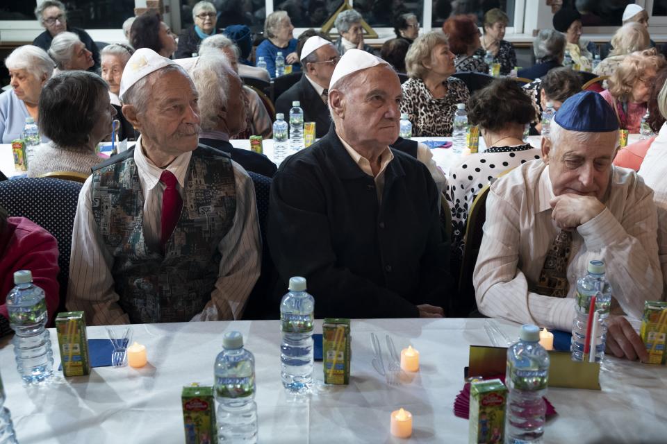 Russian Jews listen to Holocaust survivor Mikhail Spectr during the annual Hanukkah Menorah Lighting Ceremony in Moscow, Russia, Sunday, Dec. 22, 2019. Survivors of the Nazi Holocaust are gathering in four cities around the world for menorah-lighting ceremonies marking the first night of Hanukkah. (AP Photo/Alexander Zemlianichenko)