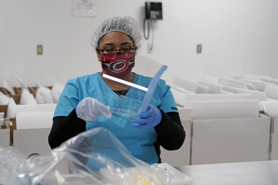 Gilero employee Anne-Marie Dutch assembles a face shield in Pittsboro, N.C., as Gov. Roy Cooper tours the facility Thursday, Dec. 3, 2020. The medical device manufacturer began producing face shields when the pandemic started and also produces swabs for rapid tests in addition to self contained oxygenated negative pressure environments. (AP Photo/Gerry Broome)