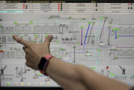 A technician explains the process of automated loading and unloading of grain at the Comvex handling and storage facility in the Black Sea port of Constanta, Romania, Tuesday, June 21, 2022. While Romania has vocally embraced the ambitious goal of turning into a main hub for the export of agricultural products from Ukraine, economic experts and port operators in the country warn that it was much easier objective to set than to actually achieve. (AP Photo/Vadim Ghirda)