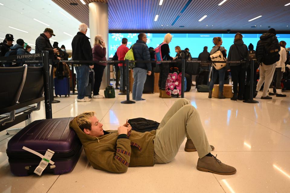 A man checks cellphone after his flight cancelation at Denver International Airport on Thursday, December 22, 2022.