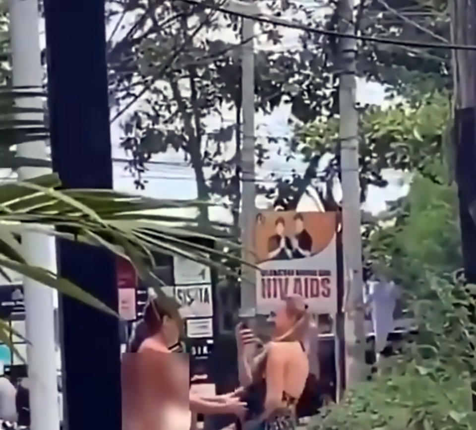 Pic Shows: Naked tourist crossing street In Bali;  Outraged Balinese authorities are trying to track down two female tourists after one of them was filmed brazenly crossing a street while totally naked.