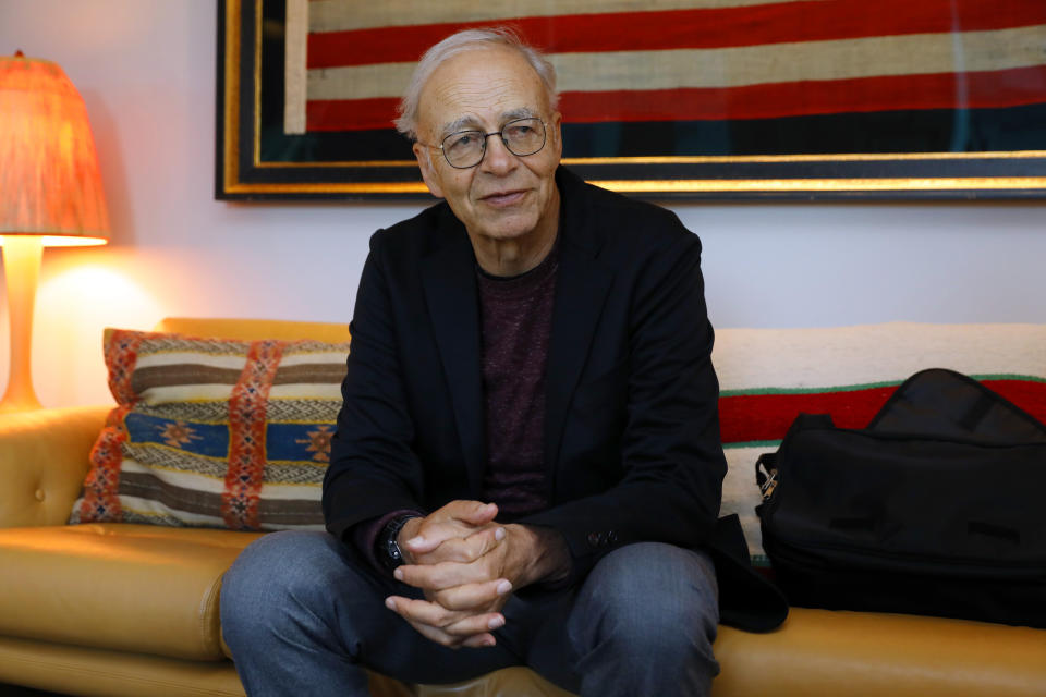 A man wearing glasses sits on a lounge with his hands clasped. (Source: AP)