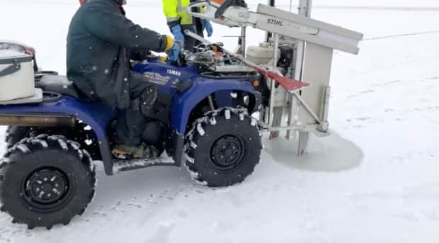 A special attachment on a tractor drills a hole in the ice. In past years some harvesting through the ice has been necessary.