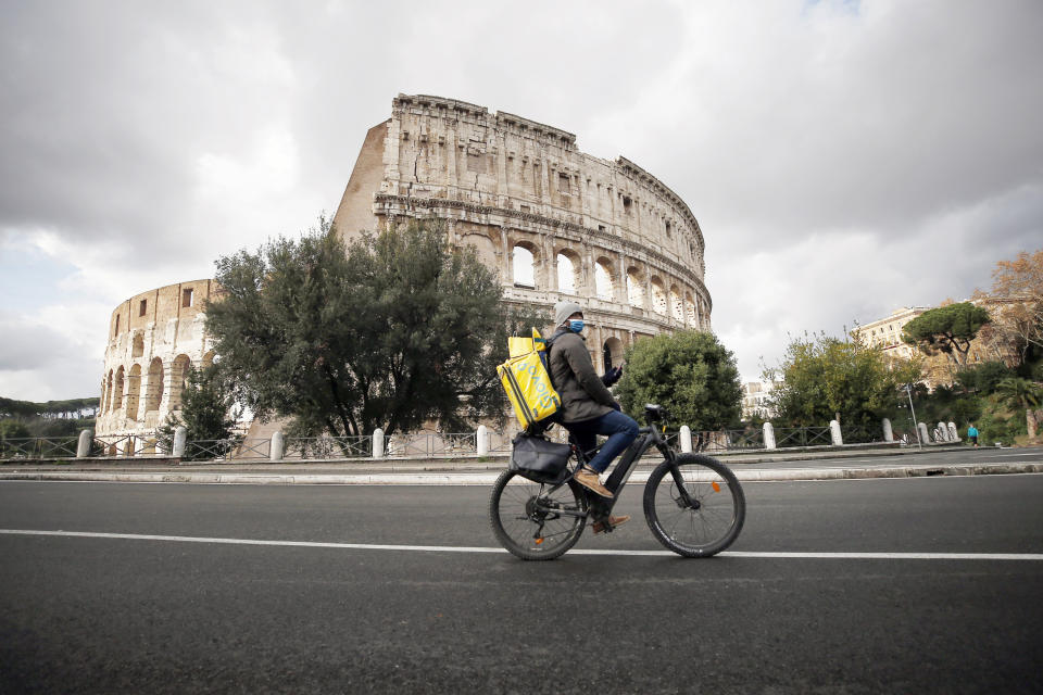 A food delivery worker cycles past the Colosseum, in Rome, Thursday, Dec. 24, 2020. Italy went into a modified nationwide lockdown Thursday for the Christmas and New Year period, with restrictions on personal movement and commercial activity similar to the 10 weeks of hard lockdown Italy imposed from March to May when the country became the epicenter of the outbreak in Europe. (Cecilia Fabiano/LaPresse via AP)