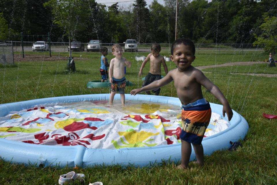 Children splash in a sprinkler during "Water Day" at Bright Light Early Care and Education on Tuesday, June 14, 2022 in Battle Creek, Mich.