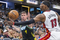 Indiana Pacers guard T.J. McConnell (9) and Miami Heat center Bam Adebayo (13) reach for the ball during the second half of an NBA basketball game in Indianapolis, Sunday, April 7, 2024. (AP Photo/Doug McSchooler)