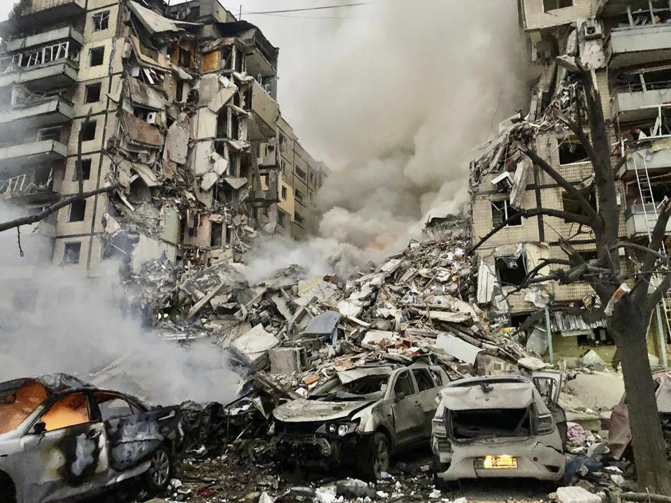 In this photo released by the Dnipro Regional Administration, smoke rises after a Russian rocket hit a multistory building leaving many people under debris in Dnipro, Ukraine, Saturday, Jan. 14, 2023. (Dnipro Regional Administration via AP)