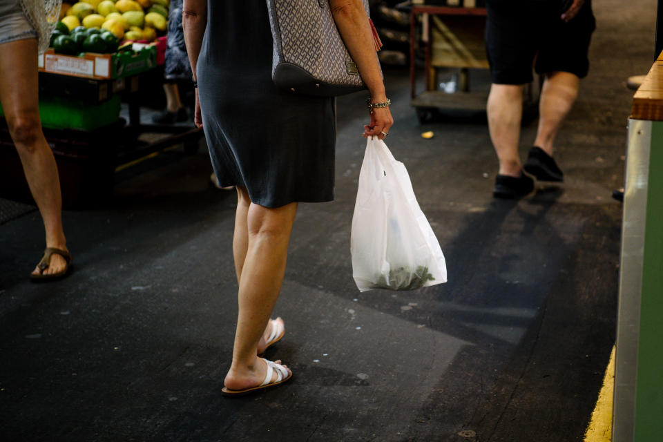 Pictured is a shopper carrying a single-use plastic bag