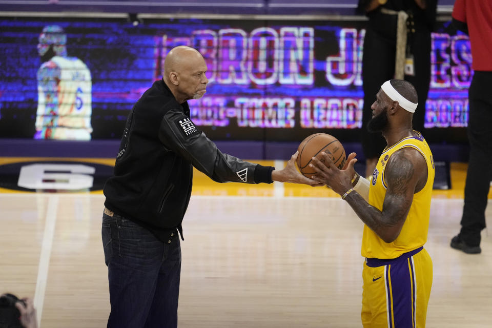 Kareem Abdul-Jabbar, left, hands the ball to Los Angeles Lakers forward LeBron James after passing Abdul-Jabbar to become the NBA's all-time leading scorer during the second half of an NBA basketball game against the Oklahoma City Thunder Tuesday, Feb. 7, 2023, in Los Angeles. (AP Photo/Marcio Jose Sanchez)