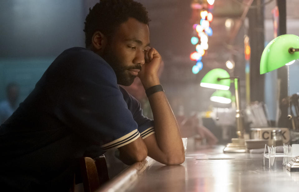 Donald Glover sitting at a bar looking reflective