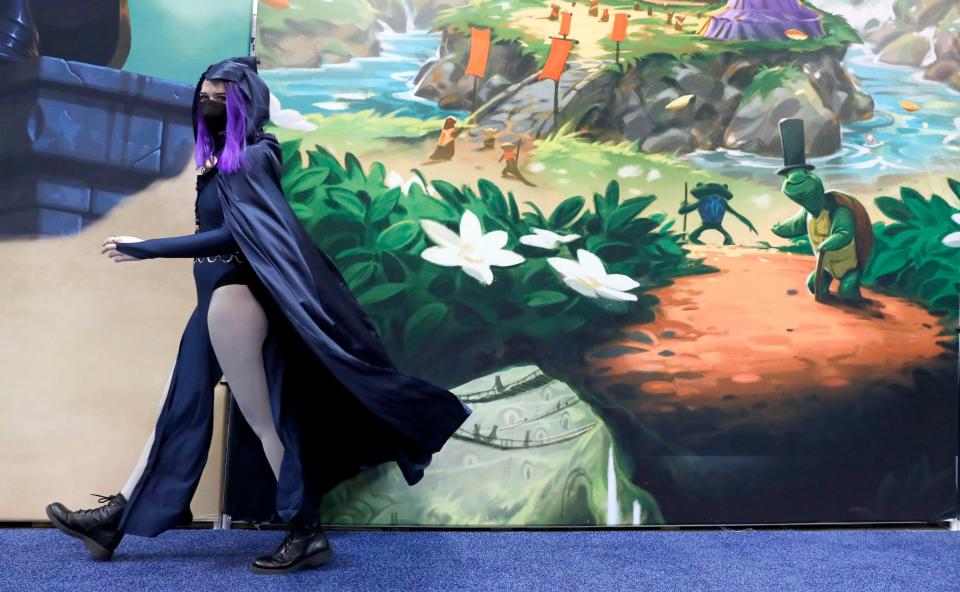 A conference attendee in a costume walks past a booth on the first day of Gen Con on Thursday, Sept. 16, 2021, at the Indianapolis Convention Center. The conference is a hybrid model, hosting both online and in-person events. Masks are required for entry. 