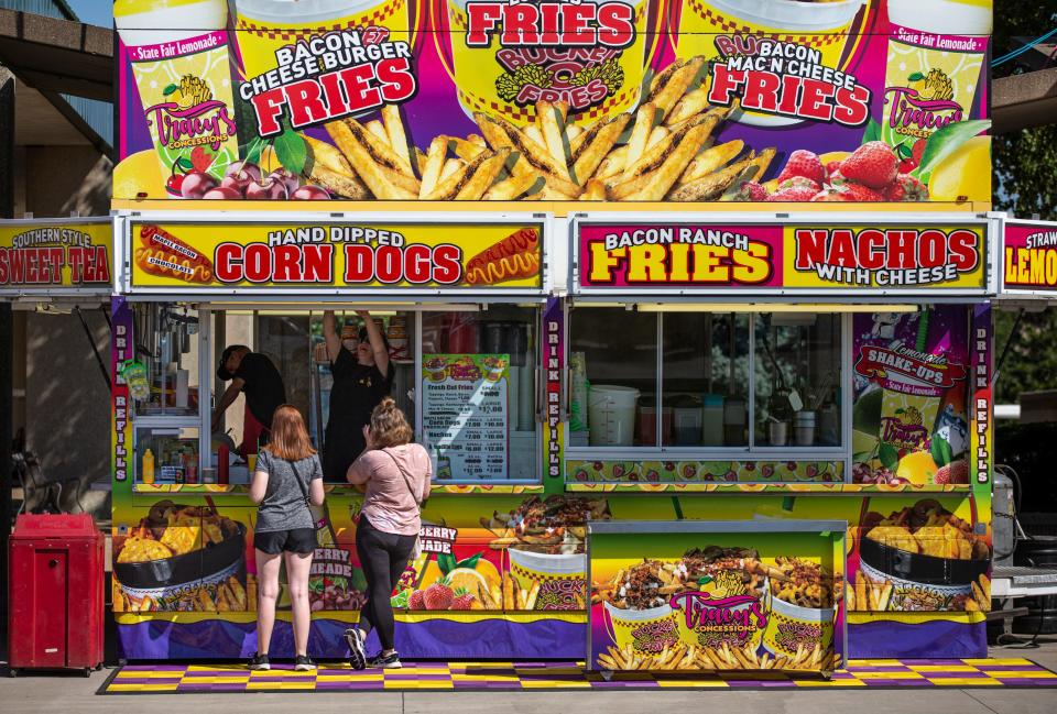 Two women order food on the midway of the Kentucky State Fair, on opening day. Aug. 18, 2022