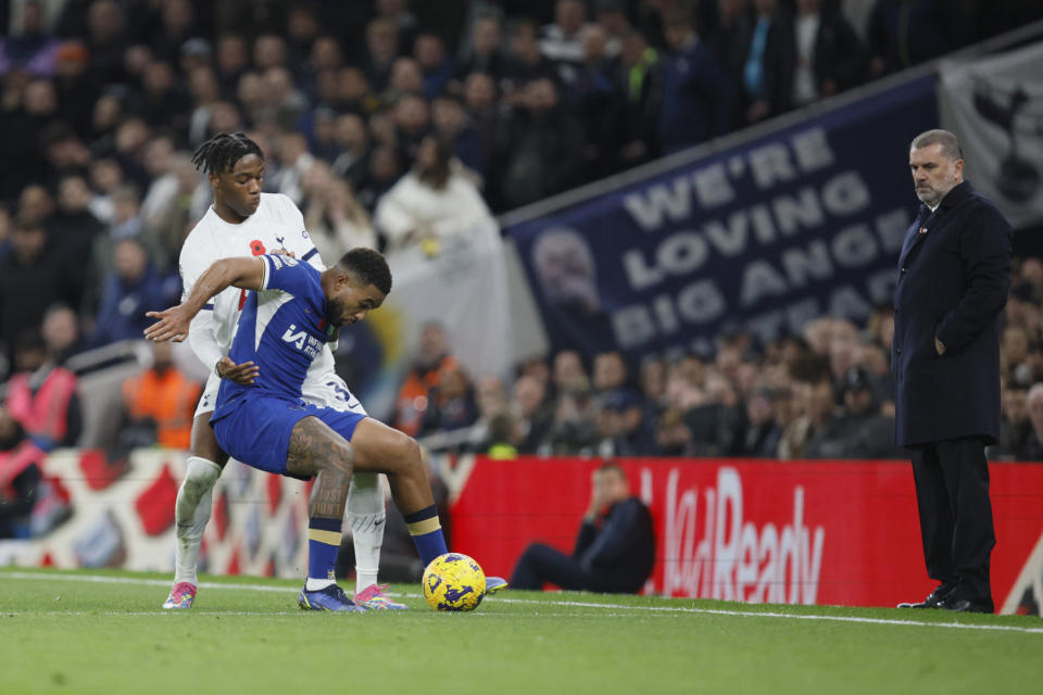 Tottenham's head coach Ange Postecoglou, right, looks on as Tottenham's Destiny Udogie, left, challenges for the ball with Chelsea's Reece James during the English Premier League soccer match between Tottenham Hotspur and Chelsea, at Tottenham Hotspur Stadium, London, Monday, Nov. 6, 2023. (AP Photo/David Cliff)