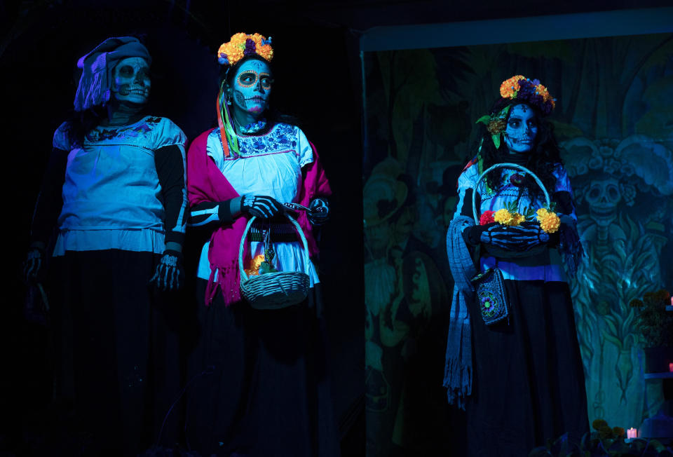 Women dressed as "Catrinas" perform in a play promoting the upcoming Day of the Dead holiday, in the Xochimilco borough of Mexico City, Friday, Oct. 23, 2020. The iconic figures of skeletons with elegant wide-brimmed hats better known as Catrinas were created as satirical prints by Mexican artist Jose Guadalupe Posada sometime between 1910 and his death in 1913. (AP Photo/Marco Ugarte)