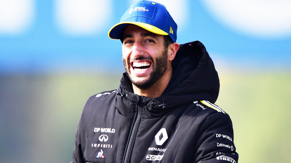 Daniel Ricciardo (pictured) smiling as he rides a bike on the F1 track.