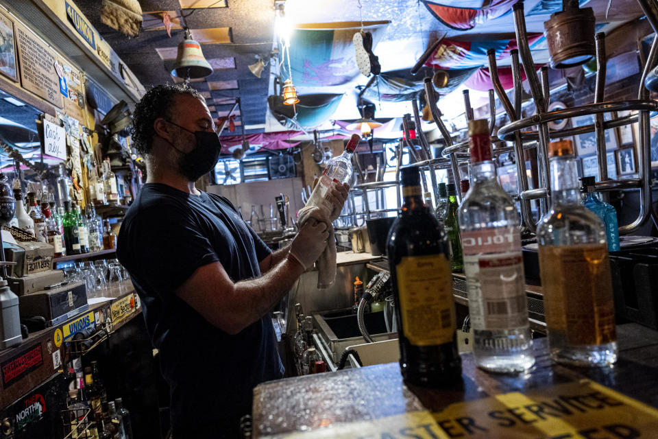 A bartender cleans bottles of liquor inside a bar in San Francisco, California, U.S., on Thursday, May 6, 2021. San Francisco advanced into the least restrictive tier of California's color-coded reopening system Tuesday, allowing most businesses to expand capacity, bars to start serving indoors and large gatherings to resume inside and outside. (David Paul Morris/Bloomberg via Getty Images)