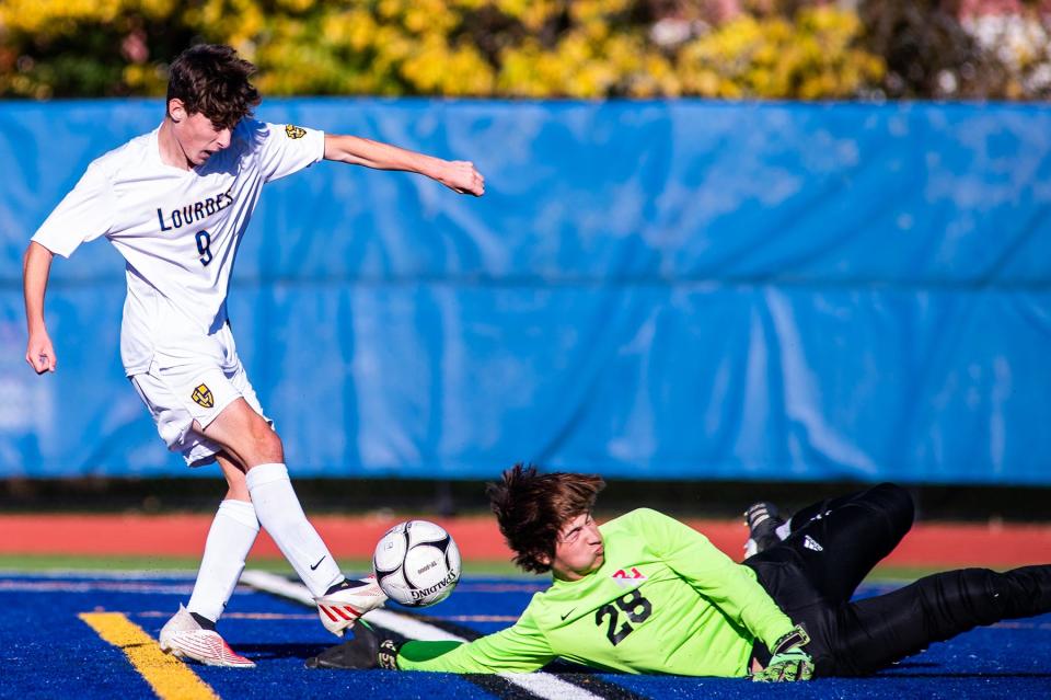 Lourdes' Anthony Geis, left, kicks the ball as Red Hook keeper Austin Litton slides to block during the boys Section 9 Class B championship soccer game in Middletown on Saturday, October 29, 2022.