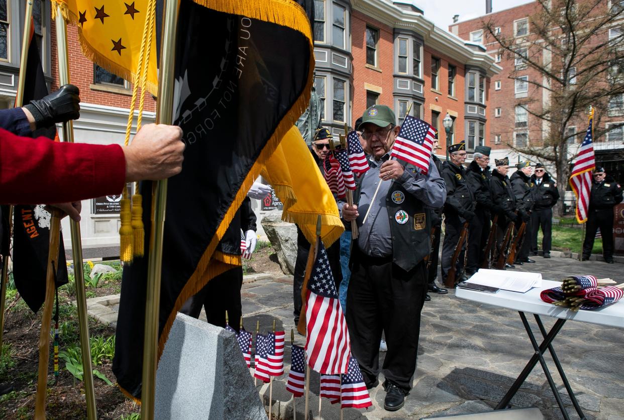 Rick Milheim, 4th District Director of the Vietnam Veterans of America, places flags on a marker as the names of Fairfield County natives who gave their lives in the Vietnam War are read. Veterans and residents attended a ceremony marking the 50th anniversary of the Vietnam War ending on March 29, 2023, in Lancaster, Ohio.