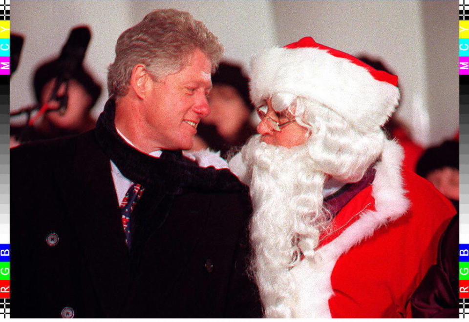 President Bill Clinton speaks with Santa Claus, played by TV personality Willard Scott, after lighting the 1996 national Christmas tree in Washington. Clinton took part in a celebration for the first night of Hanukkah at the White House. (Photo credit should read JOYCE NALTCHAYAN/AFP/Getty Images)