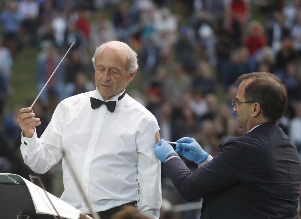 Ivan Fischer, founder of the Budapest's Festival Orchestra, receives his third dose of the COVID-19 vaccine as he conducts the orchestra, during a free concert in Budapest, Hungary, Wednesday August 25, 2021. The Budapest Festival Orchestra promoted the need for booster shots and encouraged Hungarians to stay alert since the risk of becoming infected is still high as the delta variant spreads. AP Photo/Laszlo Balogh