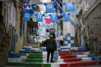 A woman walks among banners and writings in support of Napoli soccer team in downtown Naples, Italy, Tuesday, April 18, 2023. It's a celebration more than 30 years in the making, and historically superstitious Napoli fans are already painting the city blue in anticipation of the team's first Italian league title since the days when Diego Maradona played for the club. (AP Photo/Andrew Medichini)