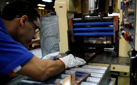 A worker from the Casa da Moeda do Brasil (Brazilian Mint) puts plates to prepare the Rio 2016 Olympic and Paralympic medals in Rio de Janeiro, Brazil, June 28, 2016. REUTERS/Sergio Moraes