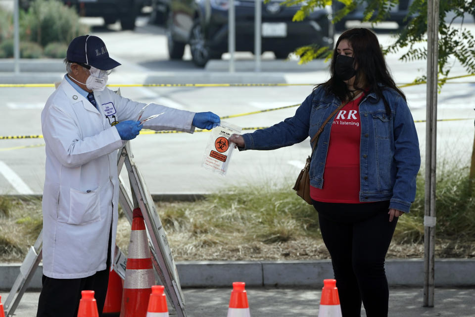 FILE - In this Jan. 7, 2021, file photo, a technician distributes a test kit at a COVID-19 walk-up testing site on the Martin Luther King Jr. Medical Campus in Los Angeles. Coronavirus deaths and cases per day in the U.S. dropped markedly over the past couple of weeks but are still running at alarmingly high levels, and the effort to snuff out COVID-19 is becoming an ever more urgent race between the vaccine and the mutating virus. (AP Photo/Marcio Jose Sanchez, File)