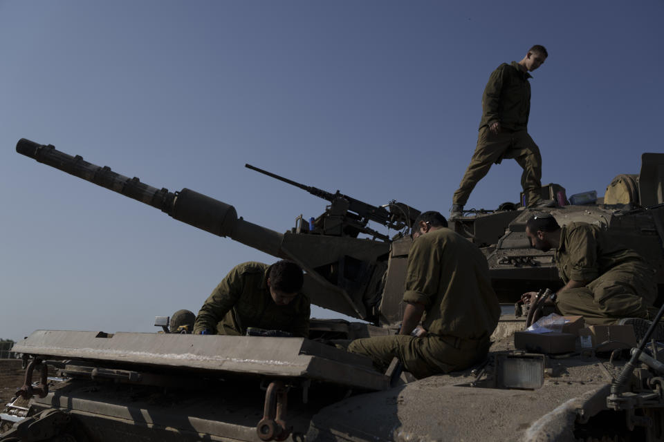 Israeli soldiers work on a tank near the Israeli-Gaza border in southern Israel, Tuesday, Jan. 16, 2024. (AP Photo/Leo Correa)