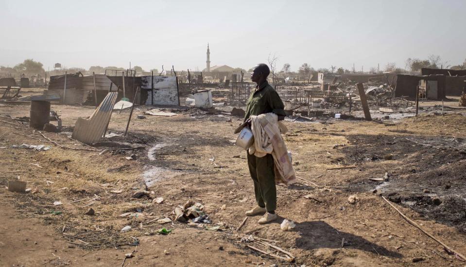 A man carrying his belongings stands amongst the remains of buildings destroyed by the recent fighting, after government forces on Friday retook from rebel forces the provincial capital of Bentiu, in Unity State, South Sudan Sunday, Jan 12, 2014. On Sunday senior South Sudanese government officers inspected the recaptured town of Bentiu, in northern Unity State, that was the scene of intense fighting between government and rebel forces, while a South Sudanese government official claimed rebels had badly damaged petroleum facilities in the state. (AP Photo/Mackenzie Knowles-Coursin)