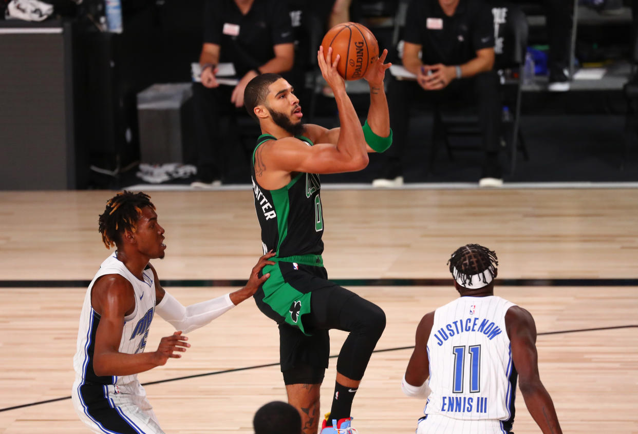 Jayson Tatum of the Boston Celtics shoots against Wes Iwundu and James Ennis III of the Orlando Magic