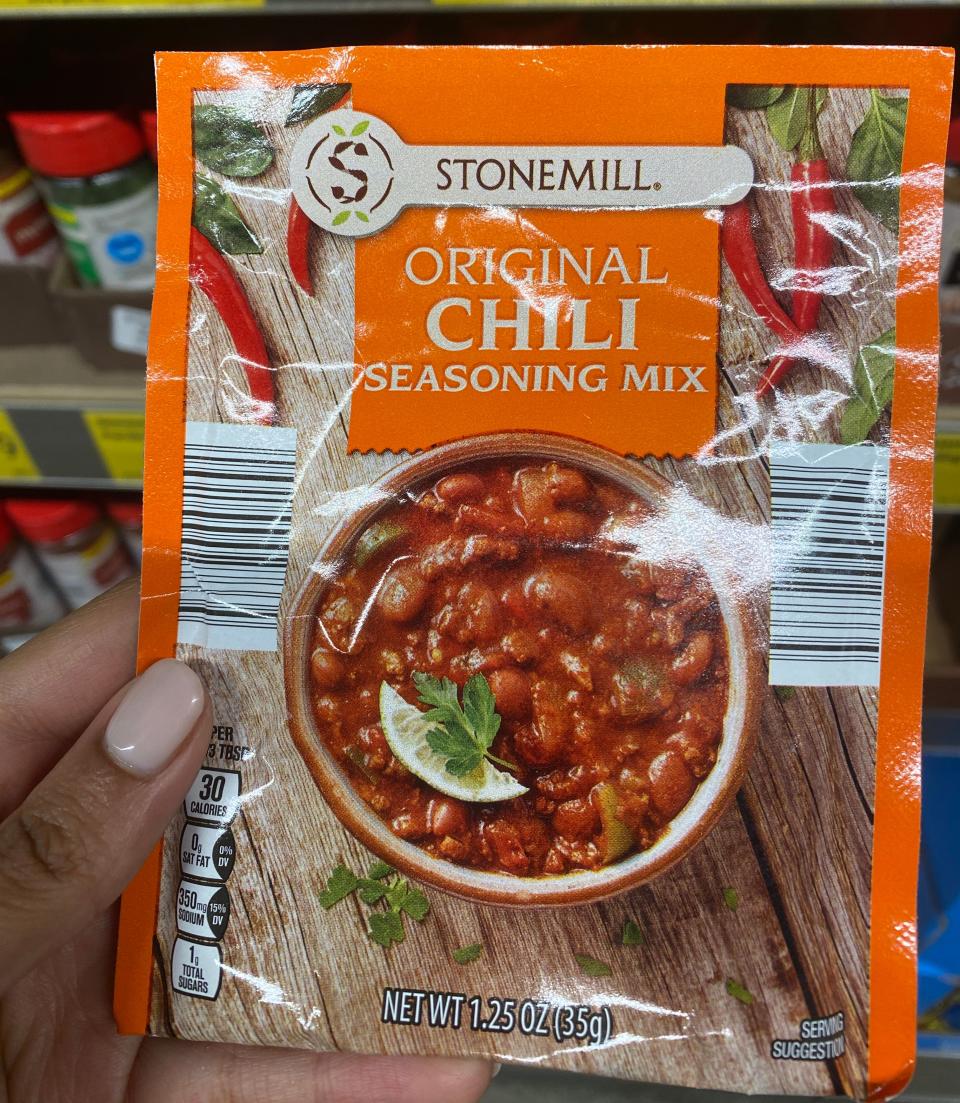 Hand holding a pack of chili seasoning at Aldi