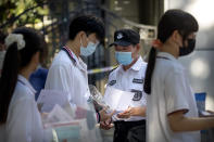 Students wearing face masks to protect against the new coronavirus have their documents checked by security officers before the first day of China's national college entrance examinations, known as the gaokao, in Beijing, Tuesday, July 7, 2020. China's college entrance exams began in Beijing on Tuesday after being delayed by a month due to the coronavirus outbreak. (AP Photo/Mark Schiefelbein)