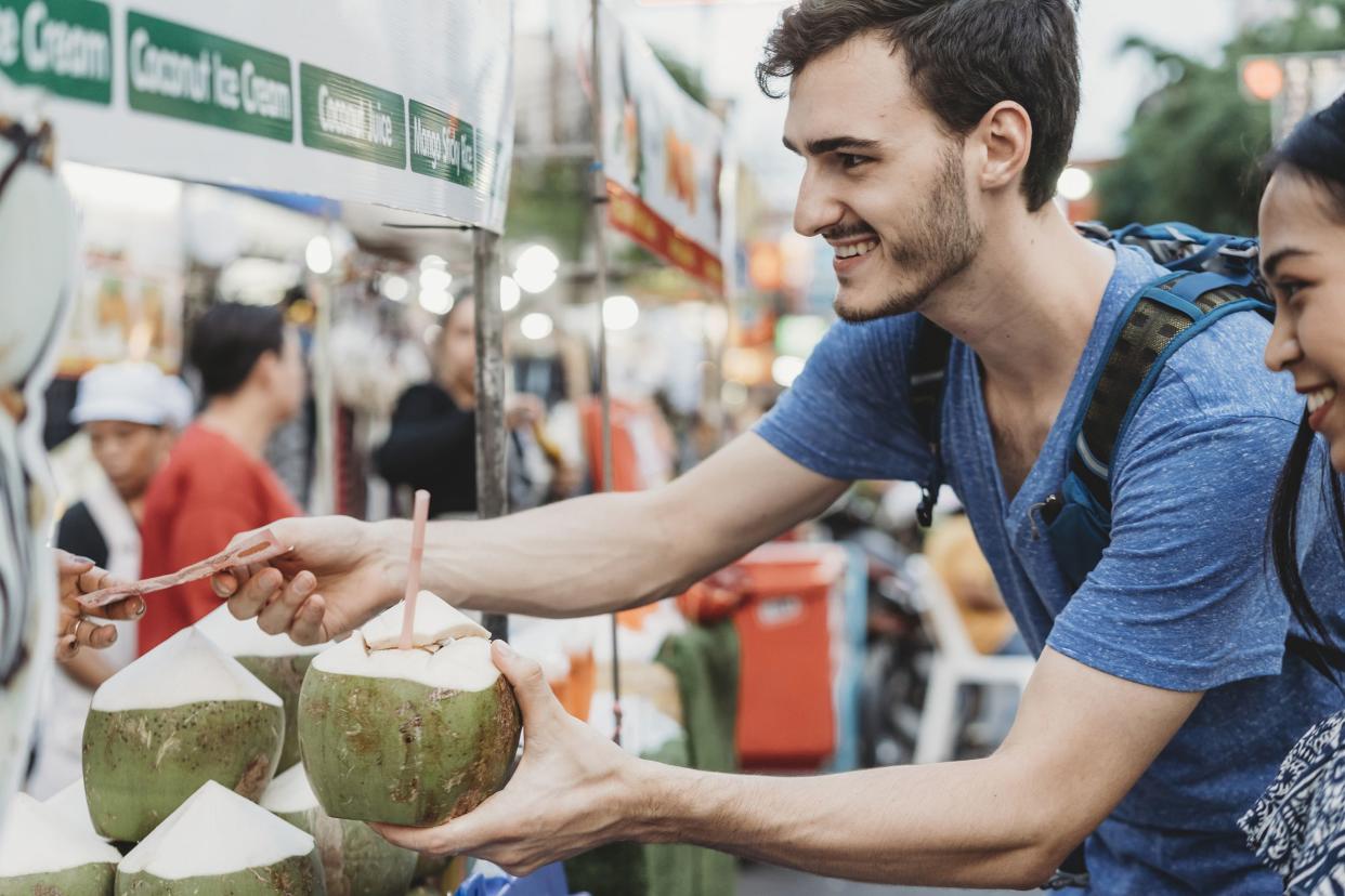 young adult man buying a coconut drink in a market