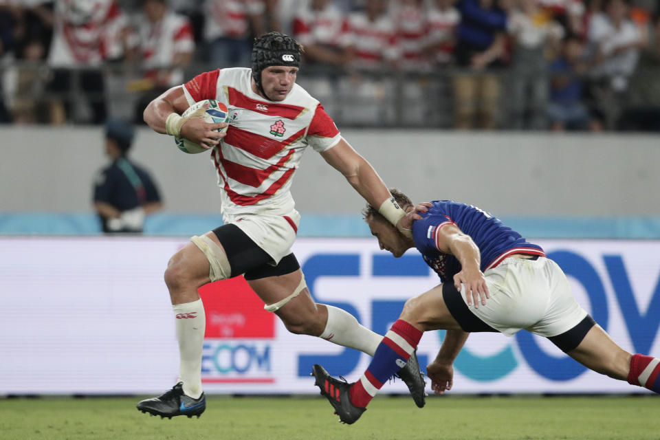 Japan's Pieter Labuschagne, left, fends off Russia's Yury Kushnarev on his way to scoring a try during the Rugby World Cup Pool A game at Tokyo Stadium in Tokyo, Friday, Sept. 20, 2019. (AP Photo/Jae Hong)