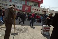 Men wash and scrub the site of the Wednesday explosion outside the Urumqi South Railway Station in Urumqi in northwest China's Xinjiang Uygur Autonomous Region on Thursday, May 1, 2014. Chinese President Xi Jinping demanded “decisive” action against terrorism after a slashing and bomb attack at a Xinjiang train station killed three people and injured 79 while the leader was wrapping up a tour of the far-western region. (AP Photo/Ng Han Guan)