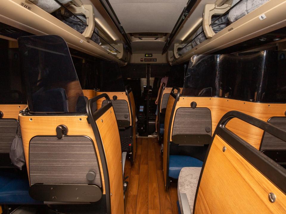 Rows of bus seats separated by boards with tray tables.