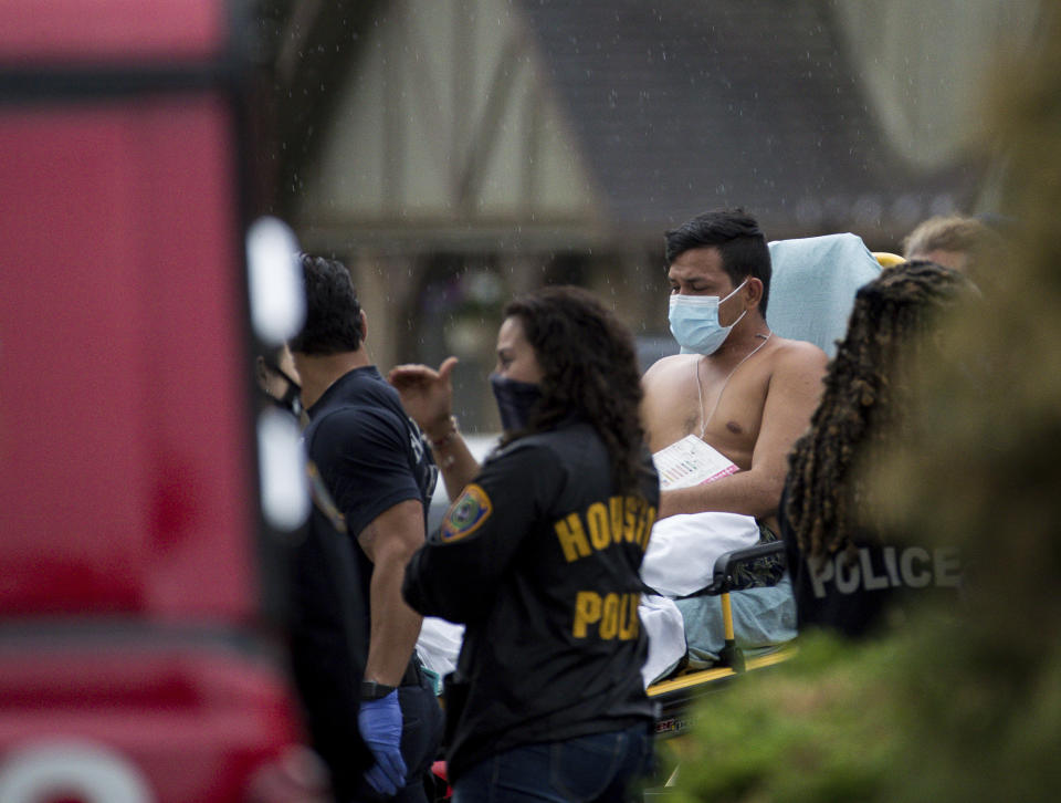 Paramedics transport a man into an ambulance from the scene of a human smuggling case, where more than 90 undocumented immigrants were found inside a home on the 12200 block of Chessington Drive, Friday, April 30, 2021, in Houston. A Houston Police official said the case will be handled by federal authorities and that some of the people inside the house were exhibiting COVID-19 symptoms. ( Godofredo A. Vásquez/Houston Chronicle via AP)