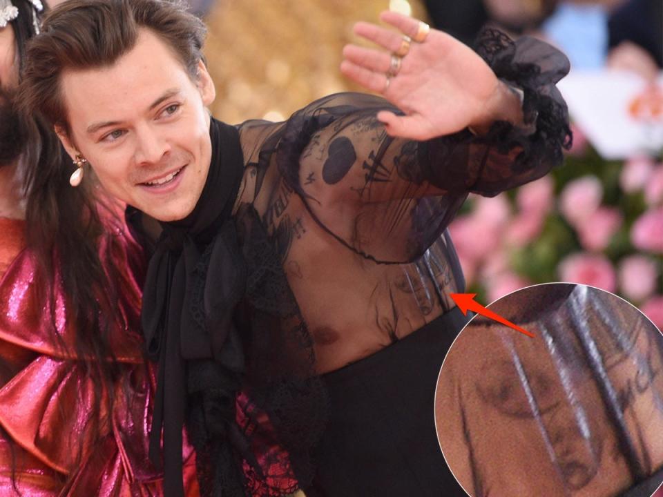 A red arrow pointing to tattoos on Harry Styles' ribcage.