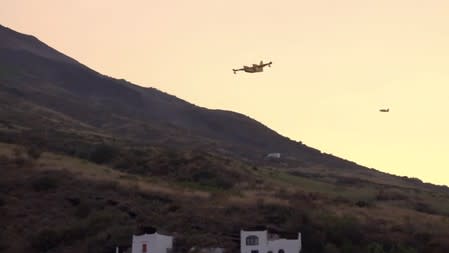 A Canadair aircraft flies over smoke that rises from the Stromboli volcano after an explosion in Stromboli