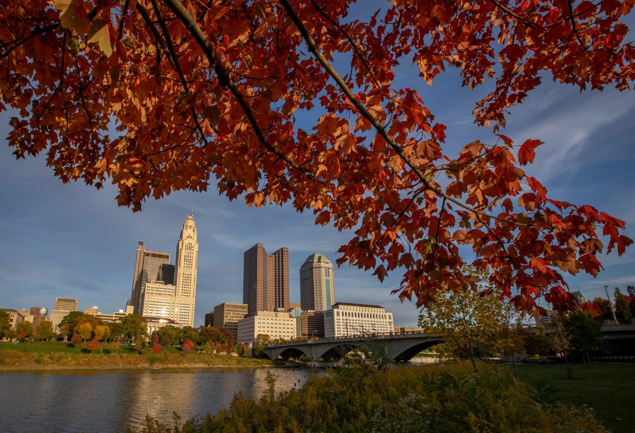 The warm tones and changing colors of fall leaves along the Scioto River frame the Downtown Columbus skyline in October 2020.