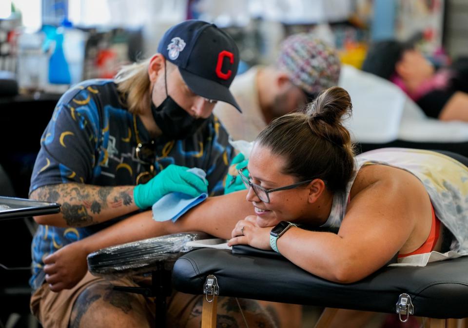 Tattoo artist Chris Naderer tattoos a fist onto Stacy Naranjo's elbow during a flash event for reproductive rights at the Golden Rule Tattoo on July 31, 2022, in Phoenix. All of the proceeds from the event will be donated to local charities that support reproductive rights.