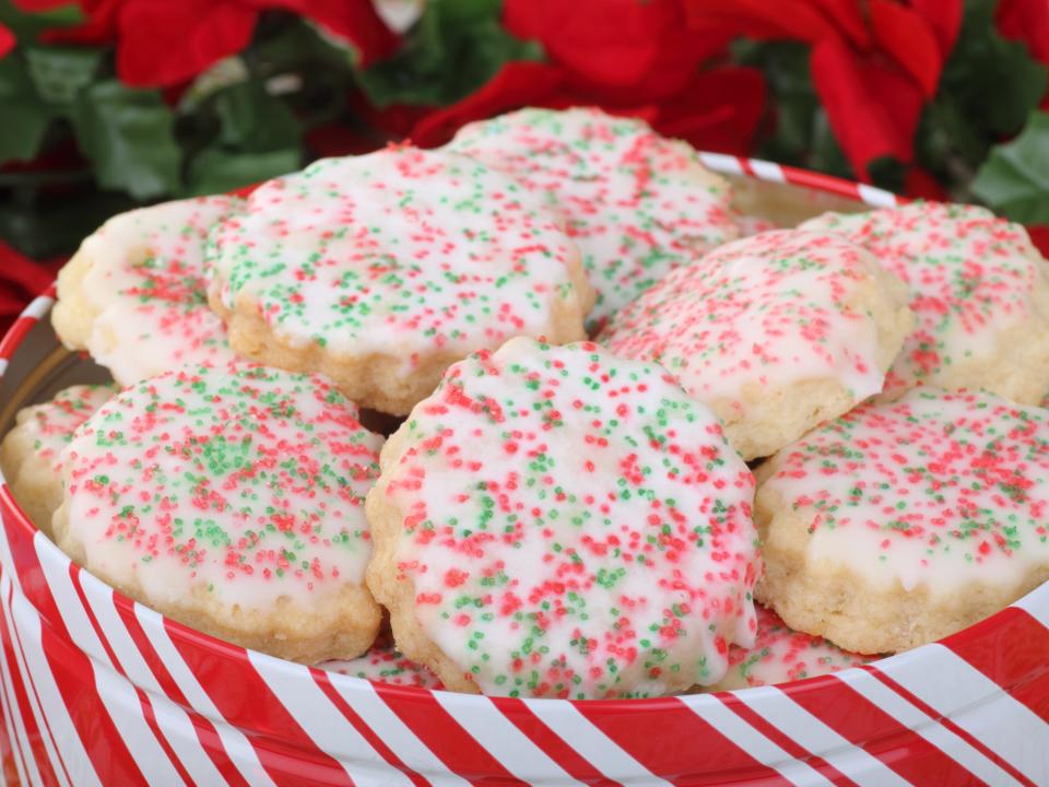 sugar cookies with red and green sprinkles in a red and white striped cookie tin