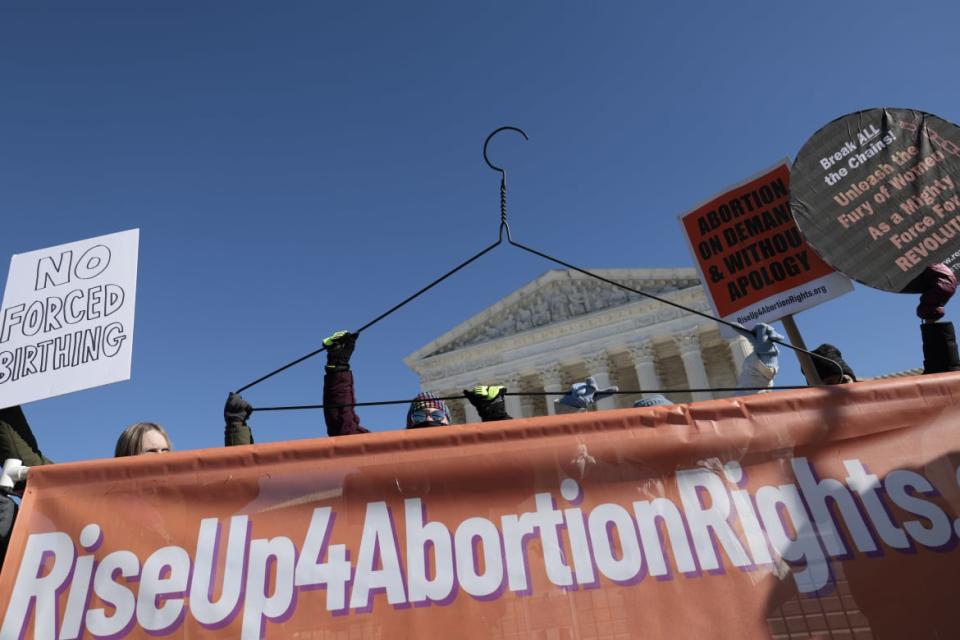 <div class="inline-image__caption"><p>Activists hold a clothes hanger at a rally in front of the U.S. Supreme Court on Jan. 22, 2022, in Washington, D.C.</p></div> <div class="inline-image__credit">Anna Moneymaker/Getty</div>