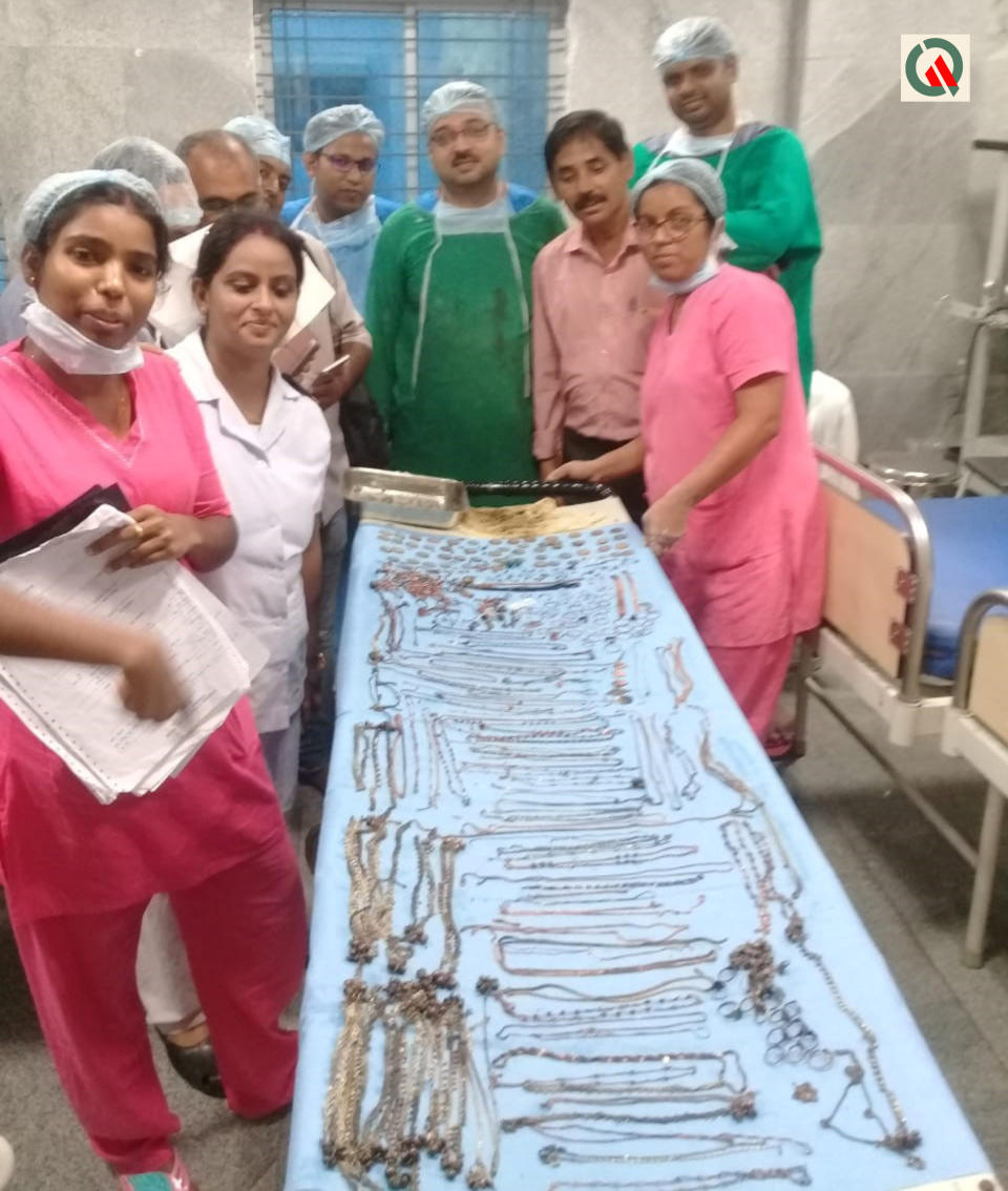 Hospital staff stands with the metal objects on a table. 