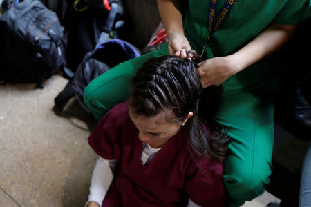 A volunteer has her hair made by a fellow volunteer while they wait for the planning of the day to help injured demonstrators in Caracas, Venezuela April 22, 2017. REUTERS/Marco Bello