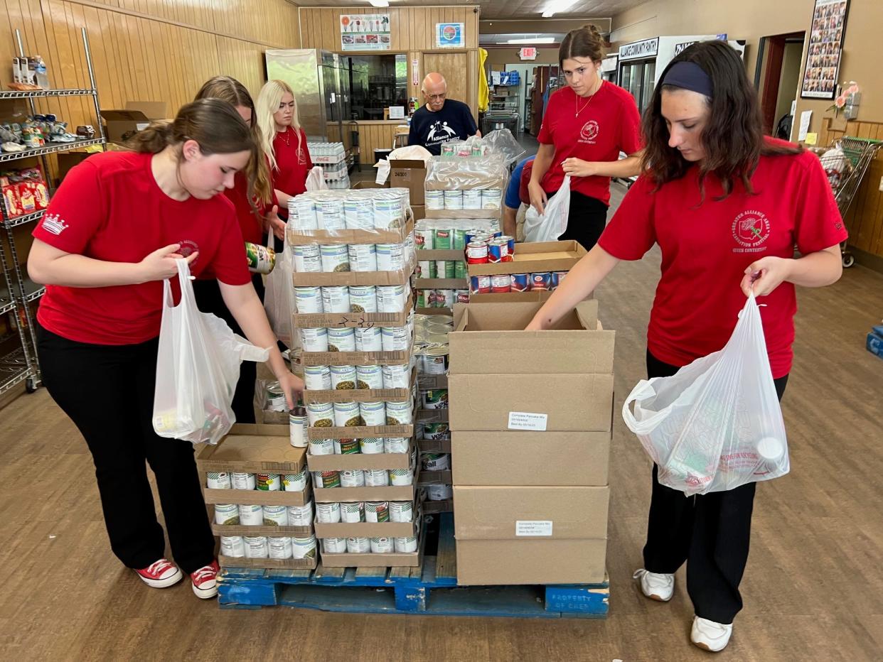 Candidates for Greater Alliance Carnation Festival queen help to pack food for clients Thursday, June 20, 2024, at Alliance Community Pantry.