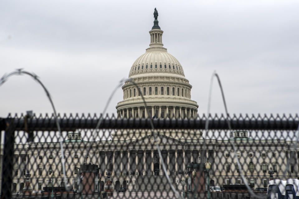 The U.S. Capitol is seen through a fence with barbed wire during the second impeachment trial of former President Donald Trump in Washington, Friday, Feb. 12, 2021. (AP Photo/Jose Luis Magana)