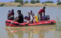 Pakistani rescue workers evacuate villagers from flooded areas of Dadu, a district in Pakistan's southern Sindh province, Sunday, Aug. 9, 2020. Pakistan's disaster management agency said three days of heavy monsoon rains that triggered flash floods have killed dozens of people in various parts of the country. (AP Photo/Pervez Masih)