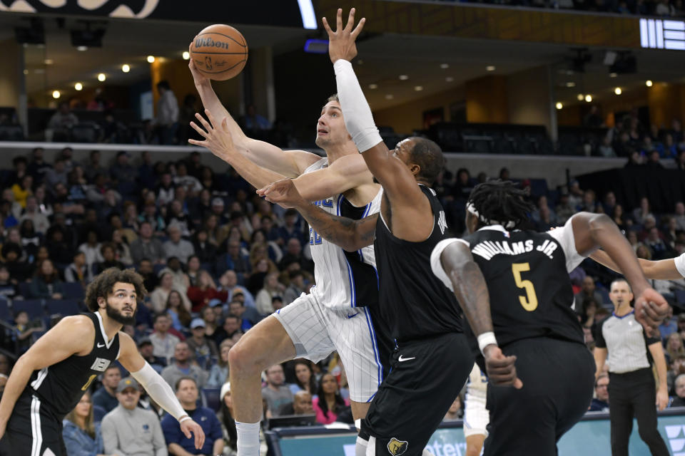 Orlando Magic forward Franz Wagner, center left, drives against Memphis Grizzlies forward Xavier Tillman, center right, in the first half of an NBA basketball game Friday, Jan. 26, 2024, in Memphis, Tenn. (AP Photo/Brandon Dill)