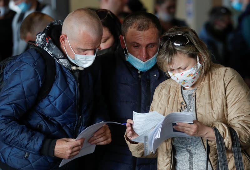 Ukrainian workers study check-in documents before their departure for Poland at an airport outside Kiev